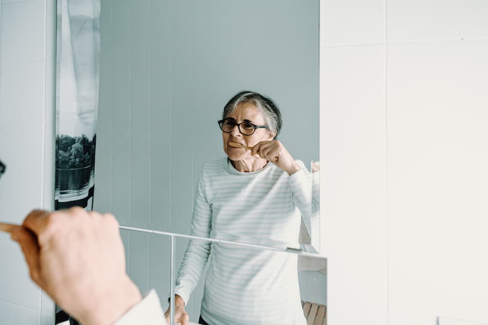 old woman washes her teeth in front of a mirror wi 2022 02 17 03 54 47 utc 1