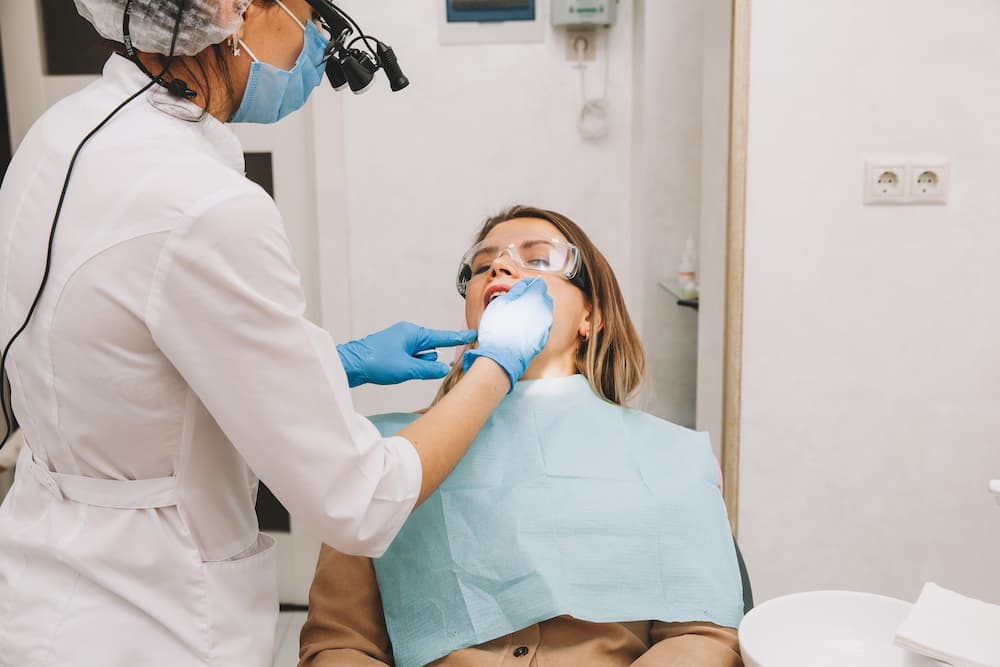 woman dentist treats teeth of a young woman lying 2022 02 01 09 50 04 utc 1
